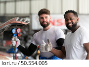 Car mechanic working in an auto repair shop, inspecting the operation of the car’s air conditioner and refrigerant. Стоковое фото, агентство Ingram Publishing / Фотобанк Лори