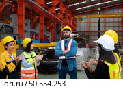 Supervisor and group of factory workers wearing hard hats meeting brief together before starting the day’s work. Стоковое фото, агентство Ingram Publishing / Фотобанк Лори