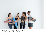 A group of female and male athletes stood and chatted amicably in the studio before beginning with the yoga class. Стоковое фото, агентство Ingram Publishing / Фотобанк Лори