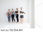 A group of female and male athletes stood and chatted amicably in the studio before beginning with the yoga class. Стоковое фото, агентство Ingram Publishing / Фотобанк Лори