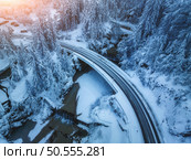 Aerial view of bridge, river with waterfalls in snowy fairy forest in winter at sunset. Top drone view of mountain road, pine trees in snow at dusk. Beautiful rural road in woods. Travel in Slovenia. Стоковое фото, агентство Ingram Publishing / Фотобанк Лори