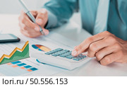Hands of businessman calculate tax with calculator while laptop computer on desk, man planning finance and investment with graph and chart, statistic and examining account, business concept. Стоковое фото, агентство Ingram Publishing / Фотобанк Лори