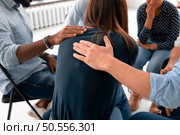 Close up back view unhappy woman with supporting diverse people at therapy session, touching shoulders, sitting in circle. Stressful businesswoman getting psychological help, trust and support. Стоковое фото, агентство Ingram Publishing / Фотобанк Лори
