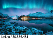 Aurora borealis over the snowy mountains, frozen sea, reflection in water at winter night in Lofoten, Norway. Northern lights and snowy rocks. Landscape with polar lights, stones, starry sky and fjord. Стоковое фото, агентство Ingram Publishing / Фотобанк Лори
