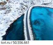 Aerial view of snowy road to the island and blue sea on both side. Bridge on snow and azure transparent water in winter. Landscape. Top drone view of road to the Henningsvaer, Lofoten islands, Norway. Стоковое фото, агентство Ingram Publishing / Фотобанк Лори