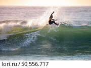 Young surfer with with wetsuit enjoying big waves. Стоковое фото, агентство Ingram Publishing / Фотобанк Лори