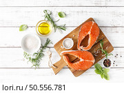 Fresh raw salmon steaks on a board with ingredients for cooking, top view. Стоковое фото, агентство Ingram Publishing / Фотобанк Лори