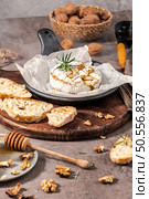 Brie type of cheese. Camembert cheese. Fresh sliced Brie cheese on a wooden tray with nuts, honey and leaves. Italian, French cheese. Стоковое фото, агентство Ingram Publishing / Фотобанк Лори
