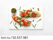 Tuna caper toasts with arugula, tomatoes and whole rye bread, top view. Стоковое фото, агентство Ingram Publishing / Фотобанк Лори
