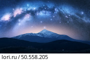 Milky Way over the beautiful Goverla mountain with snow covered peak at night in summer in Ukraine. Colorful landscape with bright starry sky with Milky Way arch, snowy rocks, hills. Space. Nature . Стоковое фото, агентство Ingram Publishing / Фотобанк Лори
