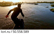Hydrofoil rider gliding over the water with his board in one of the canals of the Ria de Aveiro in Portugal during sunset. Стоковое фото, агентство Ingram Publishing / Фотобанк Лори