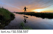Hydrofoil rider gliding over the water with his board in one of the canals of the Ria de Aveiro in Portugal during sunset. Стоковое фото, агентство Ingram Publishing / Фотобанк Лори