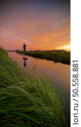 Hydrofoil rider gliding over the water with his board in one of the canals of the Ria de Aveiro in Portugal during sunset. Стоковое фото, агентство Ingram Publishing / Фотобанк Лори