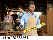 Portrait of carpenter female worker standing in front of colleague in workshop. Стоковое фото, агентство Ingram Publishing / Фотобанк Лори