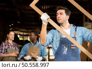Portrait of carpenter male worker standing in front of colleague in workshop, Eyesight is utilized to ensure accuracy. Стоковое фото, агентство Ingram Publishing / Фотобанк Лори