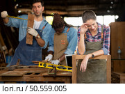 Portrait of carpenter female worker standing in front of colleague in workshop, Eyesight is utilized to ensure accuracy. Стоковое фото, агентство Ingram Publishing / Фотобанк Лори