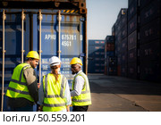 Group of workers in an empty container storage yard, The condition of the old container is being assessed to determine whether it requires maintenance for usage. Стоковое фото, агентство Ingram Publishing / Фотобанк Лори