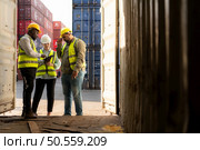 Group of workers in an empty container storage yard, The condition of the old container is being assessed to determine whether it requires maintenance for usage. Стоковое фото, агентство Ingram Publishing / Фотобанк Лори