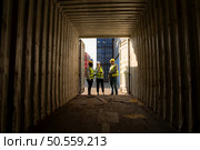 Group of workers in an empty container storage yard, The condition of the old container is being assessed to determine whether it requires maintenance for usage. Стоковое фото, агентство Ingram Publishing / Фотобанк Лори