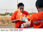 Asian paramedic giving oxygen mask to a patient in emergency situation. Стоковое фото, агентство Ingram Publishing / Фотобанк Лори