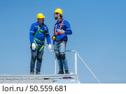 Both of technician repairing solar panels rest in the scorching sun on a factory roof covered with solar panels to receive solar energy. Стоковое фото, агентство Ingram Publishing / Фотобанк Лори