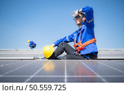 Technician repairing solar panels take off his hat and rest in the scorching sun on a factory roof covered with solar panels to receive solar energy. Стоковое фото, агентство Ingram Publishing / Фотобанк Лори