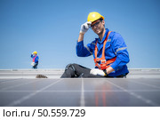 Technician repairing solar panels take off his hat and rest in the scorching sun on a factory roof covered with solar panels to receive solar energy. Стоковое фото, агентство Ingram Publishing / Фотобанк Лори