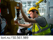 Technician who maintains a small robot arm the operation of a small robot arm used in industry is being repaired. Стоковое фото, агентство Ingram Publishing / Фотобанк Лори