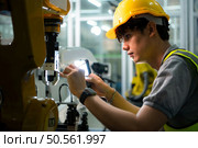 Technician who maintains a small robot arm the operation of a small robot arm used in industry is being repaired. Стоковое фото, агентство Ingram Publishing / Фотобанк Лори