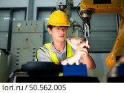 Technician who maintains a small robot arm the operation of a small robot arm used in industry is being repaired. Стоковое фото, агентство Ingram Publishing / Фотобанк Лори