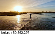 Hydrofoil rider gliding over the water with his board in one of the canals of the Ria de Aveiro in Portugal during sunset. Стоковое фото, агентство Ingram Publishing / Фотобанк Лори