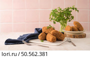 Cod dumplings, or "bolinhos de bacalhau" and parsley leaves on white ceramic dishes in a kitchen counter top. Стоковое фото, агентство Ingram Publishing / Фотобанк Лори