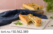 Spinach puff pastry with ricotta cheese and parsley leaves on white ceramic dishes in a kitchen counter top. Стоковое фото, агентство Ingram Publishing / Фотобанк Лори