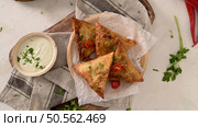 Indian samosas  - fried or baked pastry with savoury filling, popular Indian snacks, served in areca leaf dishes with spices on kitchen countertop. Стоковое фото, агентство Ingram Publishing / Фотобанк Лори