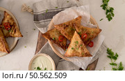 Indian samosas  - fried or baked pastry with savoury filling, popular Indian snacks, served in areca leaf dishes with spices on kitchen countertop. Стоковое фото, агентство Ingram Publishing / Фотобанк Лори