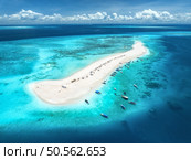 Aerial view of Nakupenda island, sandbank in ocean, white sand, boats, yachts, blue sea during low tide at sunny summer day in Zanzibar. Top view of sand spit, clear water, sky with clouds. Tropical. Стоковое фото, агентство Ingram Publishing / Фотобанк Лори