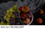 Fruits Still life with fruit on white ceramic bowl. Concrete wall. Dramatic light. Grapes, apricots and plums. Стоковое фото, агентство Ingram Publishing / Фотобанк Лори