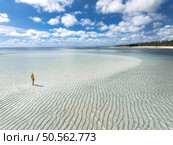 Aerial view of alone young woman on the sandbank in ocean, white sand, blue sea during low tide at sunny summer day in Zanzibar island. Top view of girl, sand spit, bay, clear water, sky with clouds. Стоковое фото, агентство Ingram Publishing / Фотобанк Лори