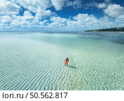 Aerial view of man on the sandbank in ocean, white sand, blue sea during low tide at sunrise in summer. Zanzibar island. Top drone view of guy, sand spit, lagoon, clear water, sky with clouds. Travel. Стоковое фото, агентство Ingram Publishing / Фотобанк Лори