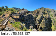 Scenic descent on a wooden staircase amidst rocky terrain under the vast blue sky. Guarda - Portugal. Стоковое фото, агентство Ingram Publishing / Фотобанк Лори