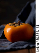 Vibrant persimmon fruit on dark backdrop with soft lighting. Стоковое фото, агентство Ingram Publishing / Фотобанк Лори
