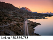 Railway station near alpine mountain Bianco lake, rocks and colorful orange sky at sunset in autumn. Bernina Express Railroad, Switzerland. Mountain valley in Alps, reflection in water in fall at dusk. Стоковое фото, агентство Ingram Publishing / Фотобанк Лори