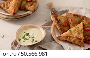 Indian samosas  - fried or baked pastry with savoury filling, popular Indian snacks, served in areca leaf dishes with spices on kitchen countertop. Стоковое фото, агентство Ingram Publishing / Фотобанк Лори