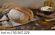 Rustic loaf of bread sits on a wooden table, surrounded by wheat stalks, flour, and a rolling pin. Стоковое фото, агентство Ingram Publishing / Фотобанк Лори