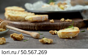 Rustic bread slices with rosemary and walnuts on a wooden board, accompanied by a honey dipper, creating a cozy and appetizing scene. Стоковое фото, агентство Ingram Publishing / Фотобанк Лори
