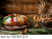 A festive King Cake adorned with colorful candied fruits, dusted with powdered sugar, and ready to be shared. Стоковое фото, агентство Ingram Publishing / Фотобанк Лори