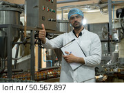 Portrait of production control supervisor inspects and controls the operation of each step in the production line of a canned fish factory. Стоковое фото, агентство Ingram Publishing / Фотобанк Лори