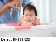 A mother bathes her little daughter in a small children’s tub. Стоковое фото, агентство Ingram Publishing / Фотобанк Лори