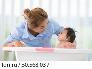 A mother bathes her little daughter in a small children’s tub. Стоковое фото, агентство Ingram Publishing / Фотобанк Лори