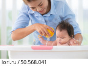 A mother bathes her little daughter in a small children’s tub. Стоковое фото, агентство Ingram Publishing / Фотобанк Лори